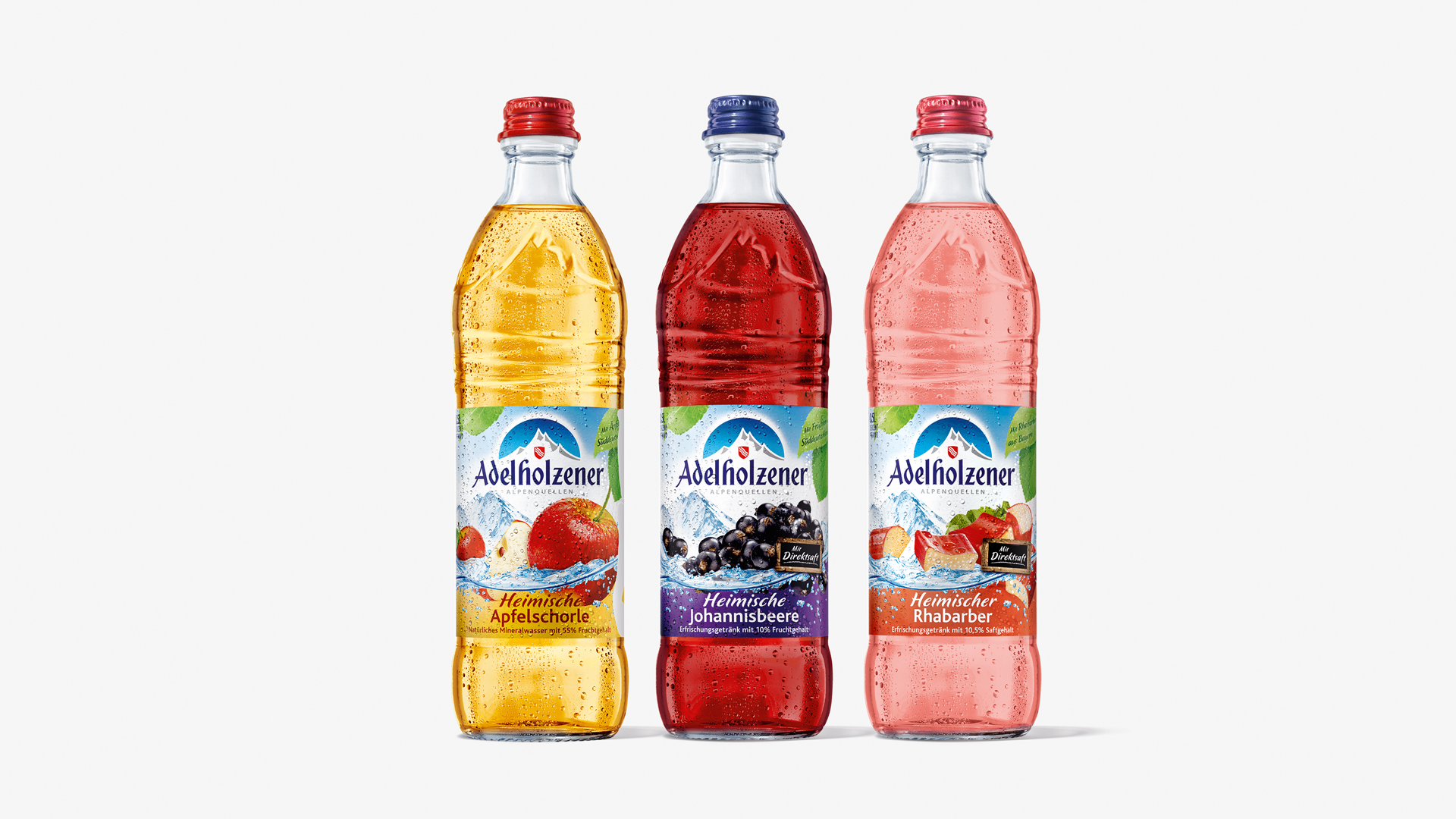 Drei Flaschen der Adelholzener Heimischen Schorlen mit Etikett im alten Design, vor weißem Hintergrund