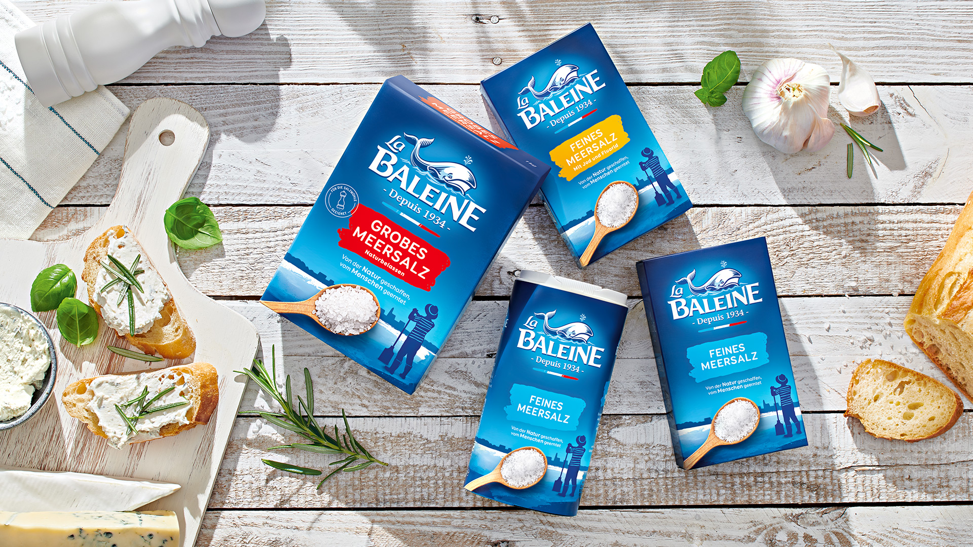 Übersicht Verpackungsdesign La Baleine Meersalz, Packungen auf Holzuntergrund mit Frühstücksszene