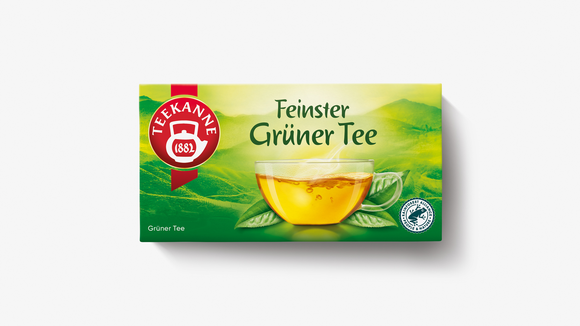 Packung des Teekanne „Feinster Grüner Tee“ vor schlichtem, weißem Hintergrund. Das Design zeigt eine dampfende Tasse mit goldgrünem Tee, eingebettet in sanft verlaufende Grüntöne mit angedeuteter Teelandschaft – natürlich, beruhigend und klar im Markenauftritt.