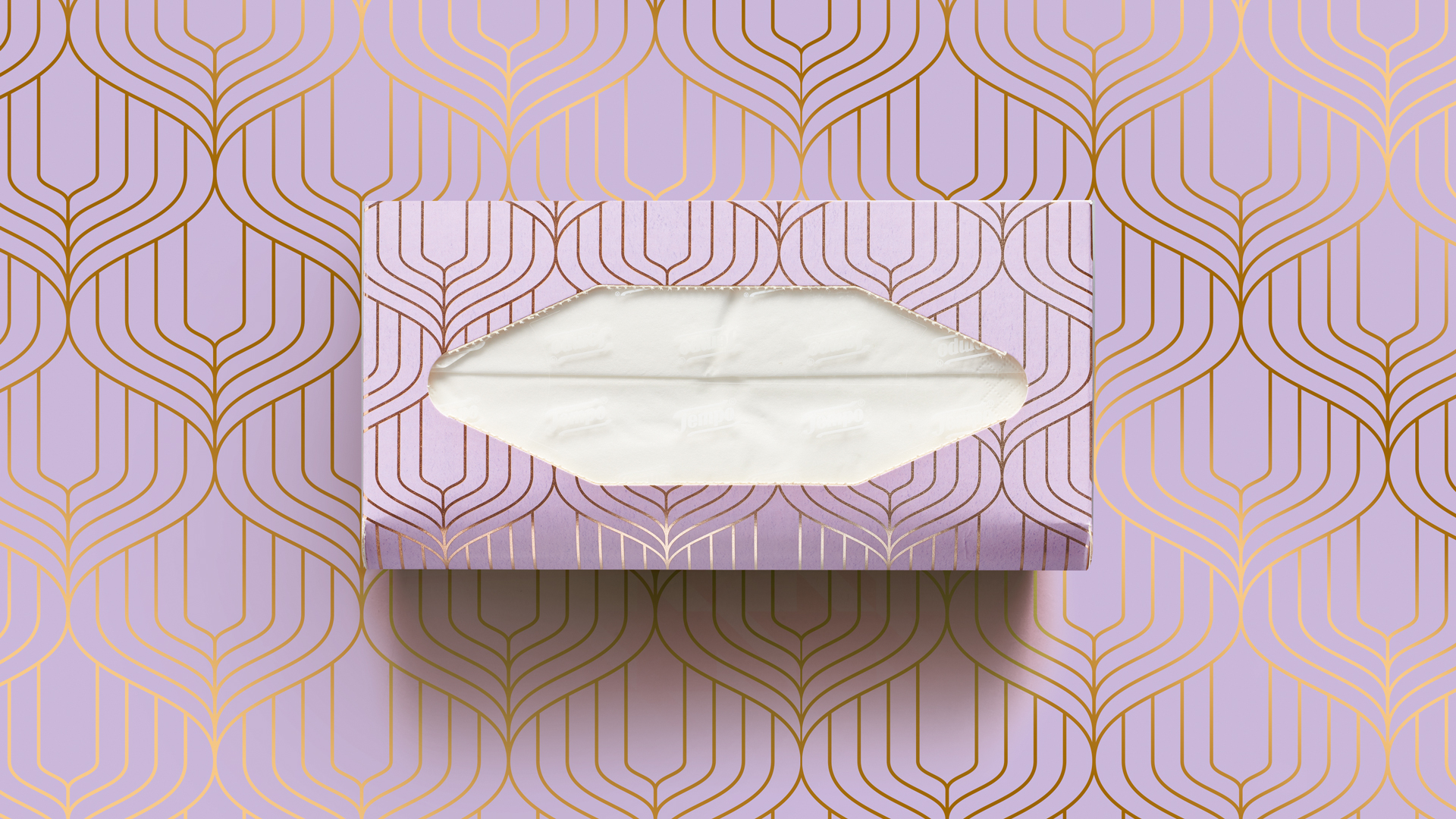 Tempo Taschentuchbox in zartem Flieder mit elegantem, goldfarbenem Art-déco-Muster – stilvoll inszeniert vor einem perfekt abgestimmten Hintergrund, der das geometrische Design der Verpackung nahtlos aufgreift und verstärkt.