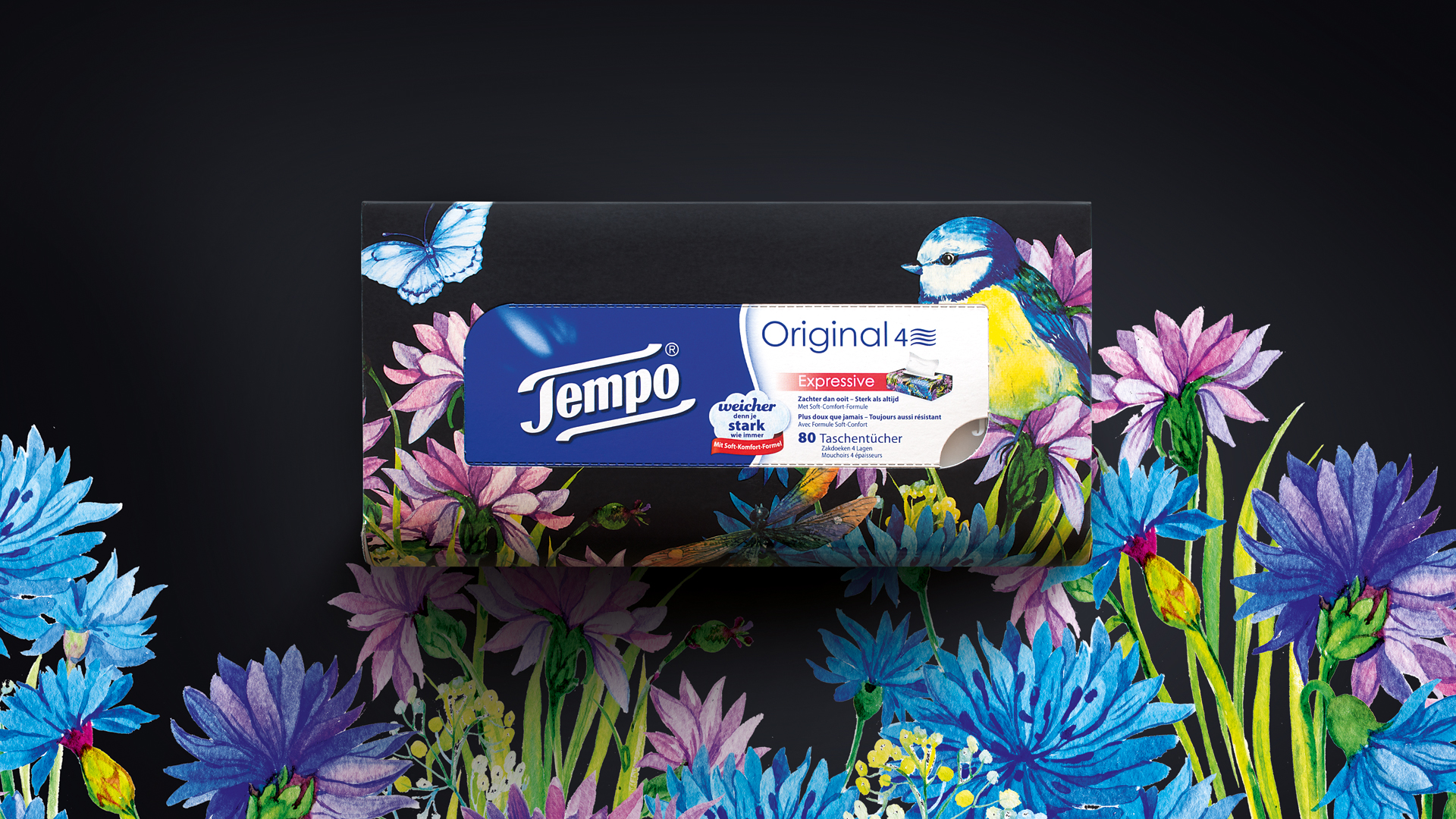 Tempo Taschentuchbox mit farbenfrohem Aquarell-Blumenmuster, Schmetterlingen und einer Blaumeise – auf tiefschwarzem Hintergrund, der die lebendigen, handgezeichneten Illustrationen in Szene setzt und der Verpackung einen ausdrucksstarken, künstlerischen Charakter verleiht.