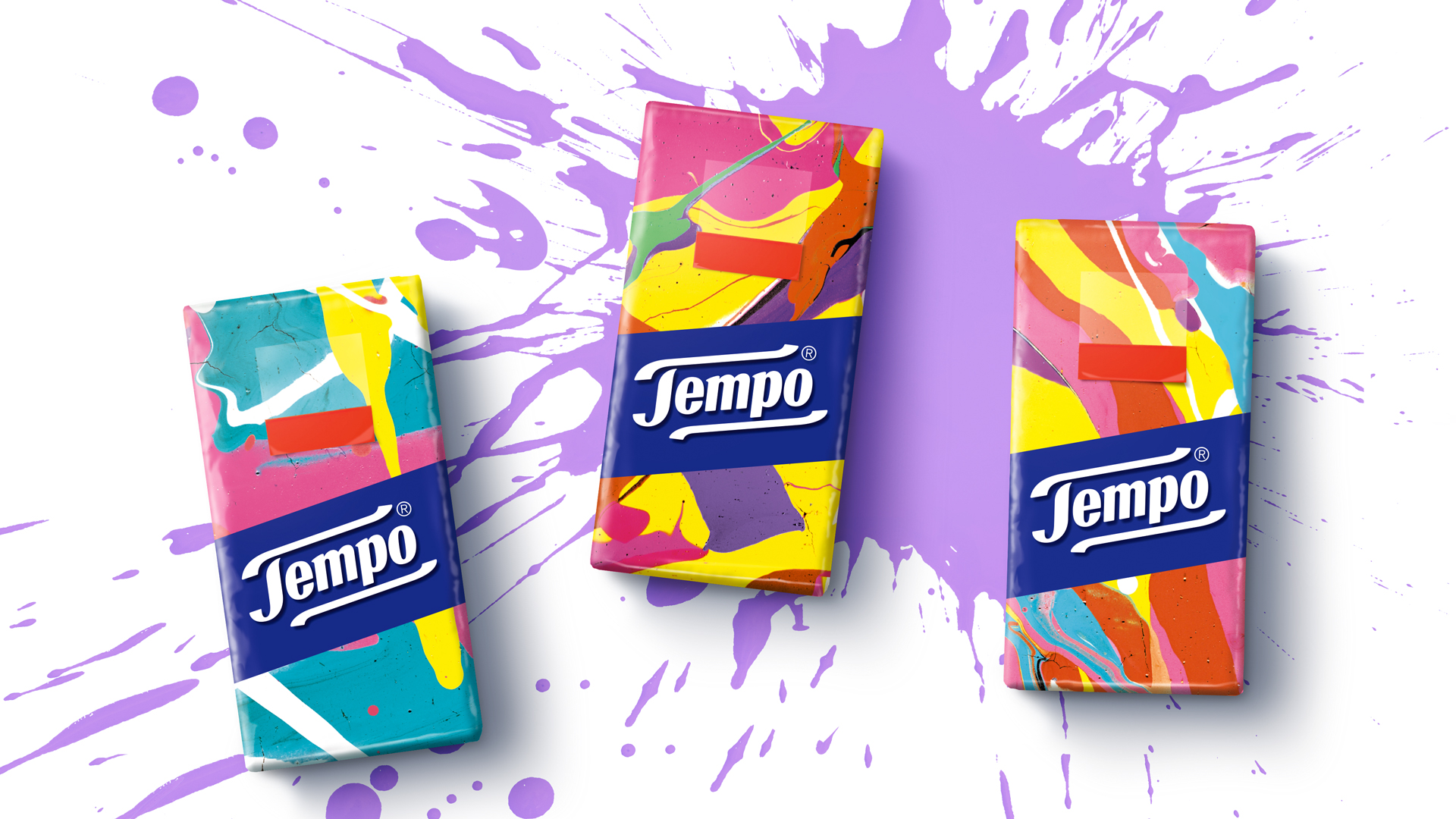 Drei Tempo Taschentuchpackungen im lebendigen, kunstvollen Splash-Design – mit farbintensiven, marmorierten Farbflächen in Pink, Gelb, Türkis, Lila und Orange, die vor einem dynamischen violetten Farbspritzer-Hintergrund platziert sind.