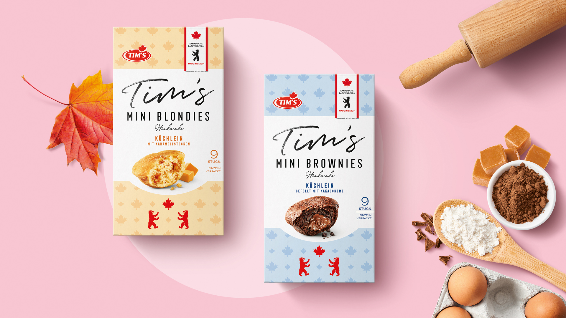 Stimmungsvolle Produktinszenierung von Tim’s Mini Blondies und Mini Brownies: Verpackungen in sanften Beige- und Blautönen auf rosa Untergrund, flankiert von herbstlichem Ahornblatt, Backzutaten und einem Nudelholz – kanadische Backtradition trifft Handmade-Charme.