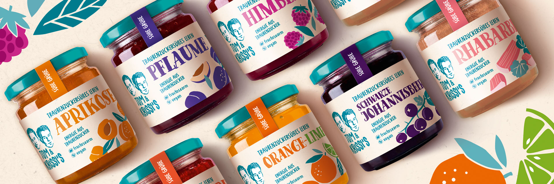 Bunte Sortenvielfalt von Tom & Krissi’s Fruchtaufstrichen auf Traubenzuckerbasis: Sechs Gläser in leuchtenden Farben – Aprikose, Pflaume, Himbeere, Rhabarber, Orange-Lime und Schwarze Johannisbeere – mit verspielten Illustrationen und typografischem Retro-Design.